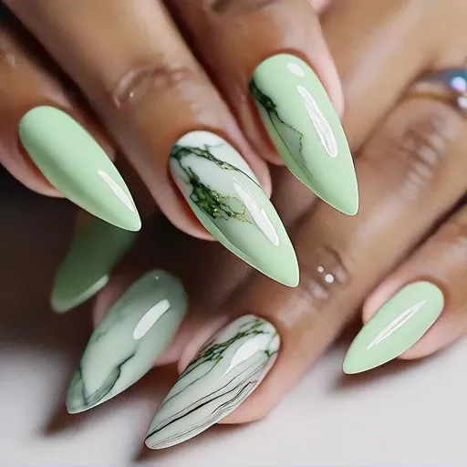 Medium-olive skin tones meet summer with a classic light green, stiletto shaped, marble technique manicure.